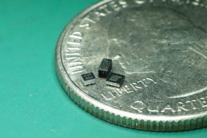 A trio of very tiny avionic components rests on a quarter.
