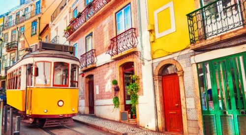 Yellow trolley in front of colorful urban homes.